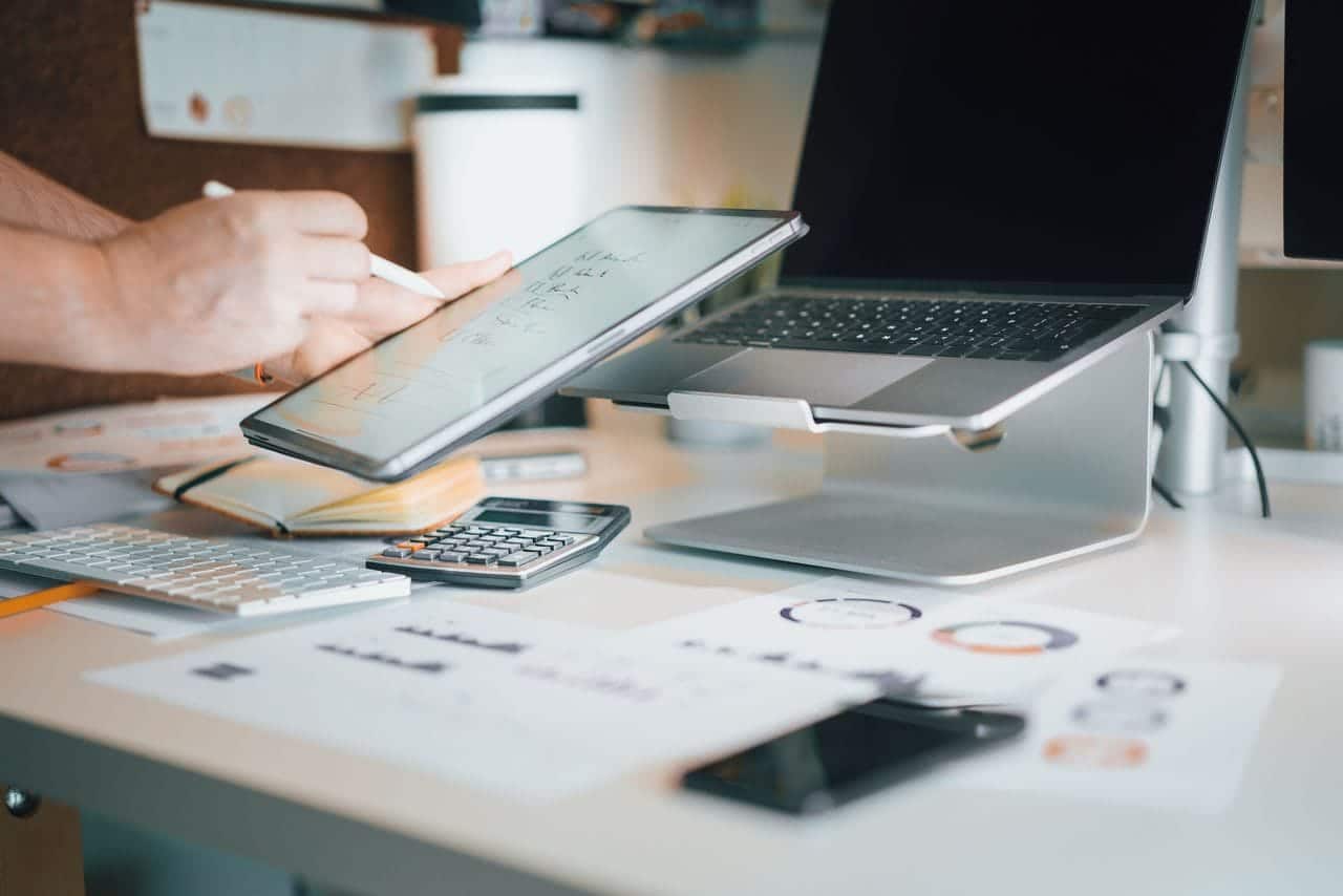 A stylish office desk setup featuring laptops, tablets, and other technological devices for productivity.